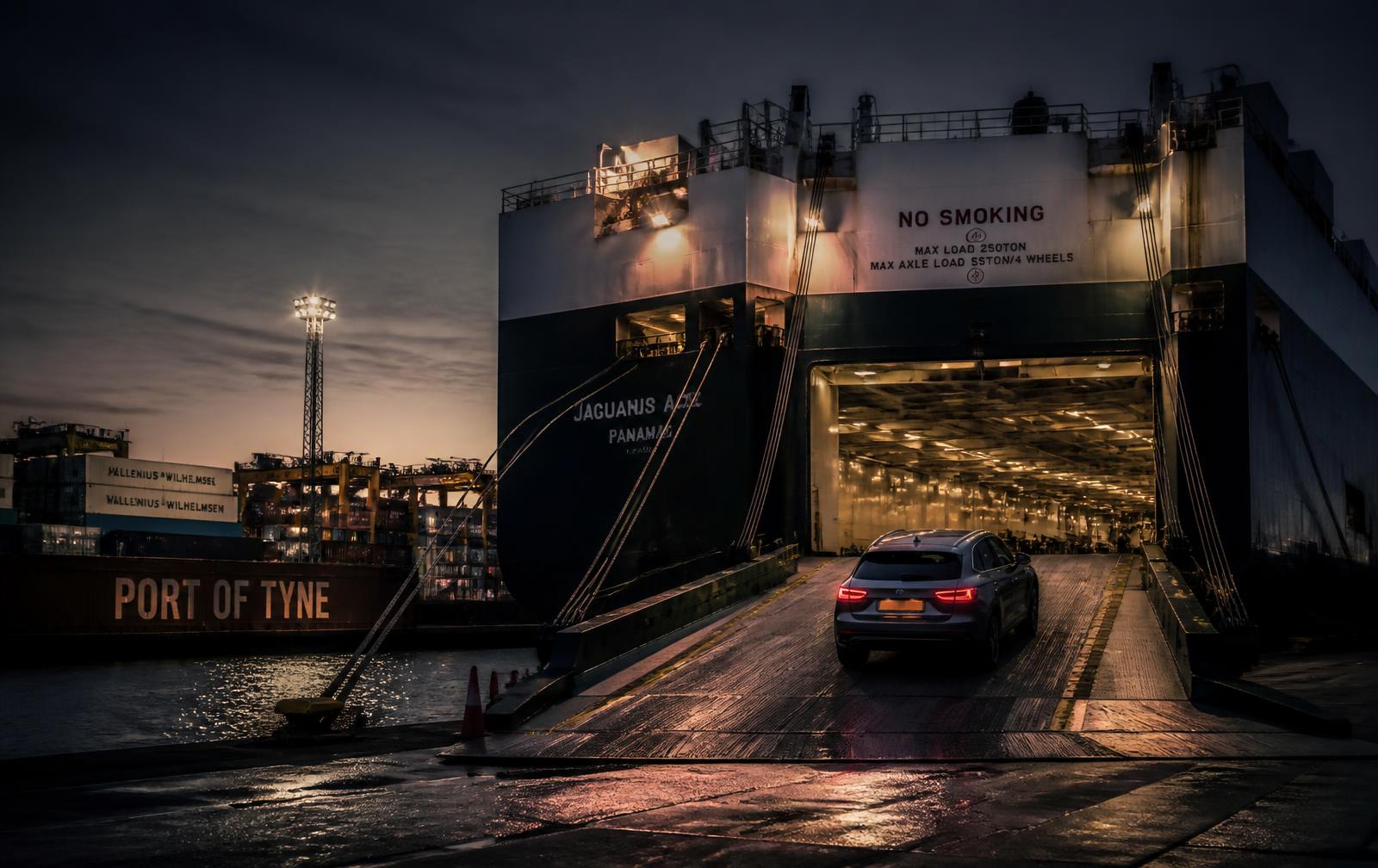 A car driving up the ramp of a roll-on roll-off cargo ship at a UK port
